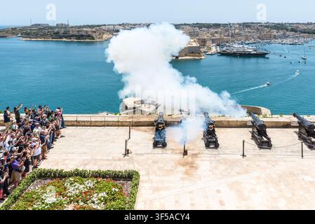 Valletta, Malte – 20 mai 2025 : Les touristes regardent la batterie historique de Saluting Battery tirer un salut de canon traditionnel à midi surplombant le Grand Harbour, le Banque D'Images