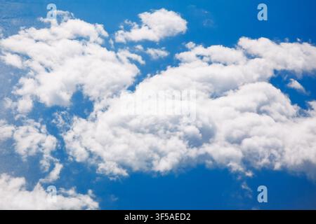 Une vue aérienne rapprochée capture des nuages cumulus denses et bouillonnants massés contre un ciel bleu vif, pris depuis la fenêtre d'un avion à l'altitude de croisière Banque D'Images