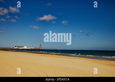 Sables dorés sur une plage à côté d'une mer d'un bleu profond avec une jetée en arrière-plan, Bournemouth, Dorset, Angleterre. Banque D'Images