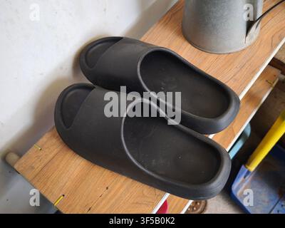 Une paire de sandales noires confortables sur un étagère en bois Banque D'Images