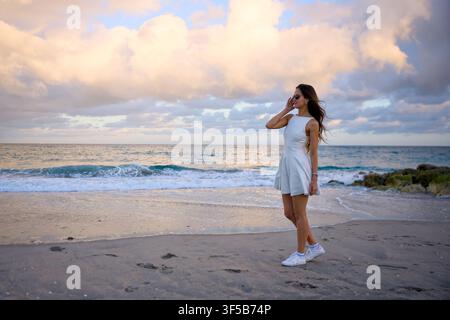 Femme debout sur une plage déserte en touchant ses cheveux Banque D'Images