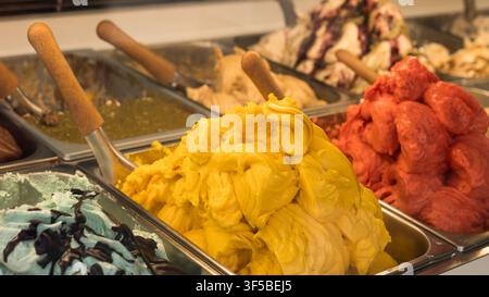 saveurs de gelato colorées empilées dans des bacs en métal au comptoir d'une crèmerie — concept : gelato artisanal, présentation de desserts, boutique de glaces Banque D'Images