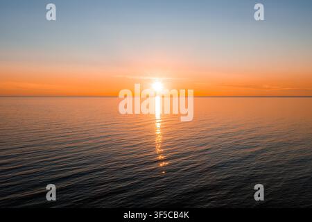 Soleil bas sur la mer Baltique près de Ventspils avec un chemin de lumière vertical Banque D'Images
