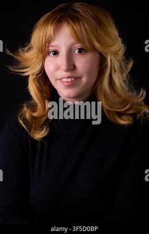 Femme souriante, portant un col roulé noir avec une coupe au carré blonde fraise dans un studio Banque D'Images