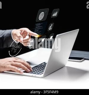 Homme d'affaires professionnel utilisant un ordinateur portable avec des icônes numériques flottantes représentant l'IA, l'automatisation, l'analyse de données et la stratégie de croissance commerciale dans un environnement sombre Banque D'Images