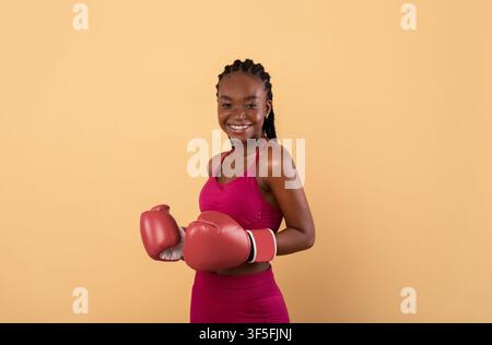Portrait d'une femme millénaire noire heureuse en vêtements de sport portant la boxe Gants Banque D'Images