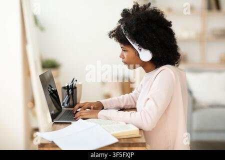 Preteen Girl faisant des devoirs sur ordinateur portable apprentissage en ligne à partir de la maison Banque D'Images