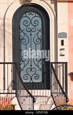 Porte d'entrée élégante en arc avec des ornements en fer forgé et un panneau de verre sur l'extérieur d'une maison de style méditerranéen. Banque D'Images