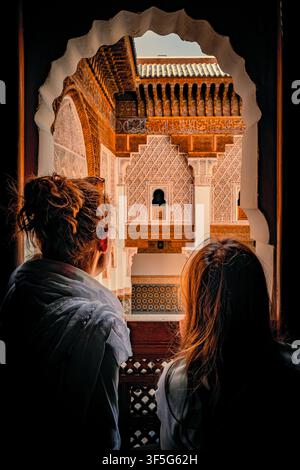 Vue magnifique de deux touristes regardant par la fenêtre de la Madrasa Ben Youssef, un ancien collège islamique dans le quartier de la Médina de Marrakech, au Maroc Banque D'Images