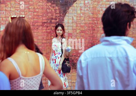 Une femme pose pour une photo devant la fresque du Baiser à Barcelone tandis que d'autres attendent leur tour Banque D'Images
