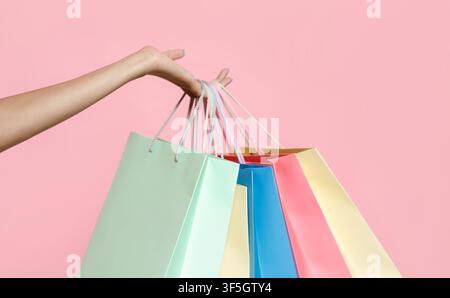 La main féminine de la jeune femme afro-américaine tient beaucoup de sacs en papier colorés avec achats Banque D'Images