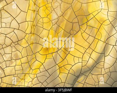 Image aérienne mettant en valeur des textures minérales vives et des motifs colorés craquelés sur une surface terreuse. L'image capture les designs complexes formés dans Banque D'Images