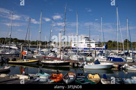 Une vue pittoresque d'un port de plaisance animé rempli de voiliers, de bateaux à moteur et d'une grande ferri à l'arrière-plan sous un ciel bleu à Lymington, Hampshire Banque D'Images