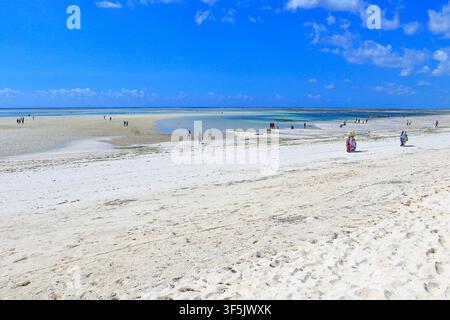 Personnes sur la plage de Pwani Mchangani à marée basse, Zanzibar, Tanzanie, Afrique de l'Est. Banque D'Images