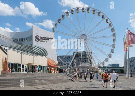 La grande roue de Cologne se trouve sur la place directement à côté du célèbre musée du chocolat de Cologne dans le Rheinauhafen. Par un temps estival ensoleillé, de nombreux piétons et touristes flânent le long de la promenade riveraine du Rhin. *** Grande roue de Cologne au musée du chocolat dans le Rheinauhafen. La grande roue de Cologne Das Kölner Riesenrad est située sur la place juste à côté du célèbre musée du chocolat de Cologne dans le quartier de Rheinauhafen. Sous un ciel d'été lumineux, de nombreux piétons et touristes se promènent le long de la promenade fluviale. Nordrhein-Westfalen Allemagne, Germany GMS20522 Banque D'Images