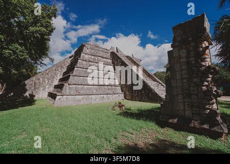 Ancienne pyramide de pierre s'élève sous un ciel bleu clair. Des marches érodées mènent vers le haut à travers une herbe verte luxuriante. La lumière du soleil scintille sur les pierres vieilles et moussues du temple. Banque D'Images