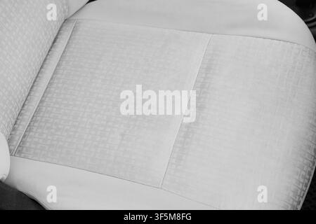 Siège auto en tissu gris clair avec motif géométrique subtil et coutures visibles, détail de l'intérieur automobile, Confort moderne et qualité des matériaux en tra Banque D'Images