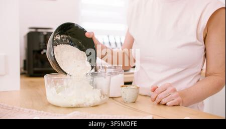 Préparation de pâte en ajoutant de la farine, main de chef, bol, maison Banque D'Images