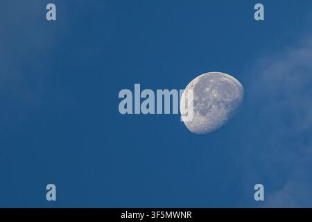 Lune croissante visible dans un ciel bleu clair diurne avec des nuages doux. Banque D'Images