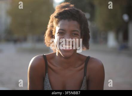 Jeune femme noire joyeuse souriant en plein air au soleil Banque D'Images