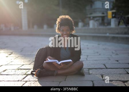 Jeune femme heureuse lisant un livre au soleil Banque D'Images
