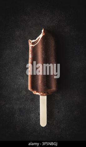 Barrette de glace au chocolat mordue sur fond sombre vue du dessus Banque D'Images