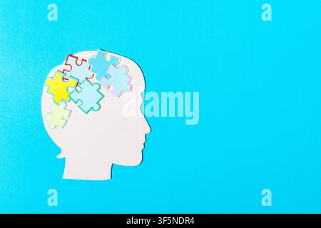 Concept artistique en découpage de papier représentant un profil humain avec des pièces de puzzle symbolisant la santé mentale. Banque D'Images