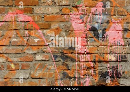Texture de mur de briques avec des éclaboussures et gouttes de peinture en aérosol graffiti rose vif. Fond de maçonnerie vieilli avec des éléments d'art de rue colorés sur une surface rugueuse Banque D'Images