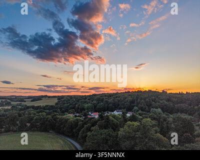 ciel dramatique au coucher du soleil au-dessus d'un paysage de campagne boisé avec des nuages colorés du soir Banque D'Images