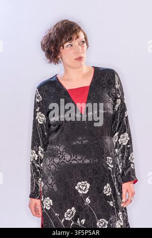 Rachel McCrum est dans un studio portant une robe noire à fleurs blanches, regardant pensivement l'appareil photo. Le fond est clair et simple, mettant l'accent Banque D'Images