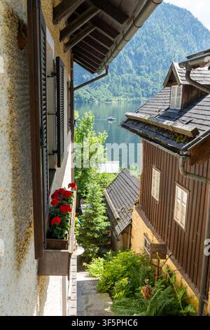 Rue étroite, vieilles maisons alpines aux volets en bois, fleurs et vue panoramique sur le lac dans un village de montagne. Banque D'Images