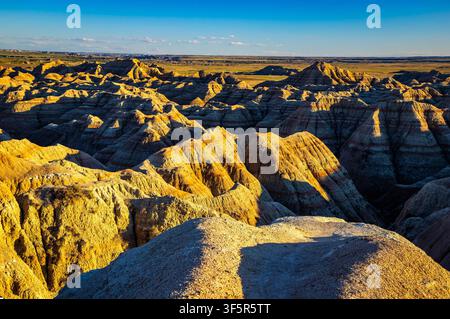 Vue panoramique des formations rocheuses érodées colorées et superposées et de la prairie dorée du parc national des Badlands, Dakota du Sud Banque D'Images