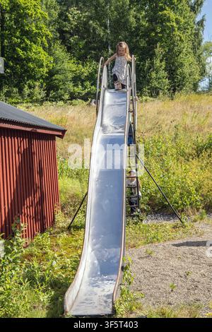 Des enfants jouent sur un toboggan à la campagne. Banque D'Images