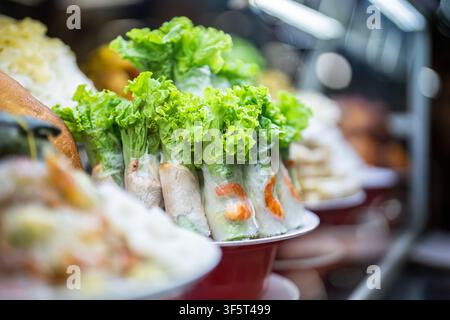 Présentation d'un plat de fast-food fait main avec des spring rolls en papier de riz aux herbes et aux crevettes au marché. Banque D'Images