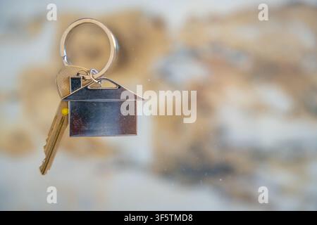 Clés de maison avec un porte-clés en forme de maison accroché à un crochet mural. Concept d'achat immobilier, d'emménagement dans une nouvelle maison et de propriété immobilière. Banque D'Images