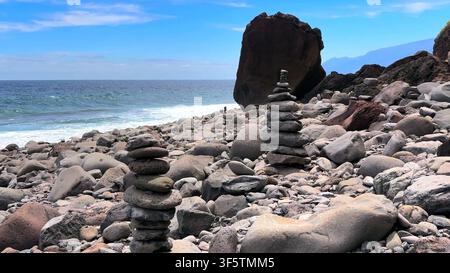 Cairns en pierre équilibrés sur une côte volcanique rocheuse avec l'océan Atlantique en arrière-plan sur l'île de Madère. Banque D'Images