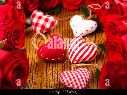 Cœurs colorés avec des roses rouges sur fond en bois pour la Saint-Valentin, un anniversaire ou la fête des mères Banque D'Images