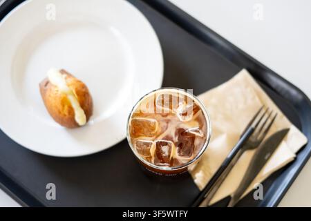 Un café glacé et une madeleine fourrée servis sur un plateau dans un café moderne à Gangnam, Séoul. Banque D'Images