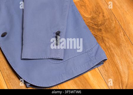 Close-up d'une manche et des boutons d'un blazer bleu sur un plancher en bois, photographié à Nottingham, Angleterre, Royaume-Uni le 8 juin 2015. Banque D'Images