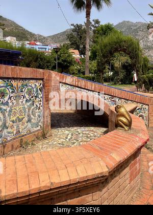 Beau jardin à Chefchaouen, Maroc, présentant une arche décorative de verdure encadrant une fontaine carrelée, 4 août 2025 Banque D'Images