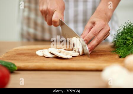 Femme coupant des champignons frais sur une planche à découper en bois Banque D'Images