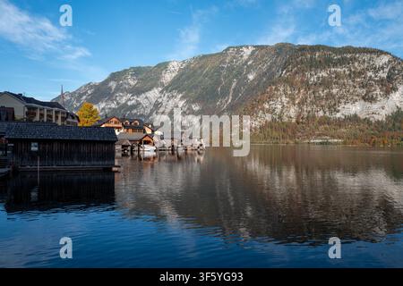 Lac alpin de Hallstatt, Autriche. Un village avec des maisons à bateaux en bois et une eau calme et réfléchissante sous un ciel bleu. Banque D'Images