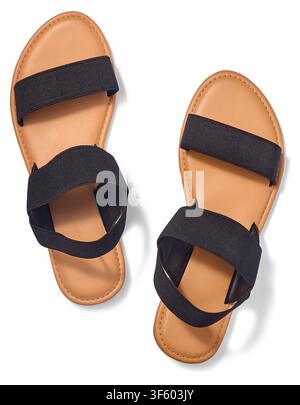 Paire de sandales pour femmes isolées sur fond blanc, sangles élastiques noires et semelles plates brun tan, chaussures d'été tendance en vue de dessus Banque D'Images