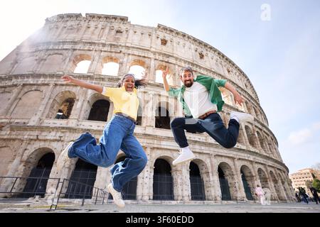 Heureux couple sautant devant le Colisée de Rome. Banque D'Images