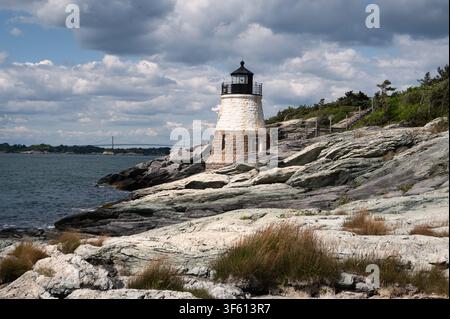 Phare de Castle Hill, Newport, Rhode Island, avec un avant-plan rocheux, un ciel nuageux, le pont Claiborne Pell en arrière-plan Banque D'Images