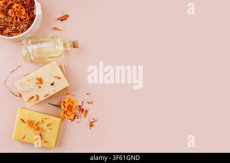 Savon aux herbes fait main et bouteille d'huile sur un fond beige doux Banque D'Images