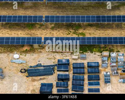 Vue aérienne d'une ferme solaire en construction avec des rangées de panneaux photovoltaïques, des piles de modules solaires et des matériaux de construction au sol dans Banque D'Images