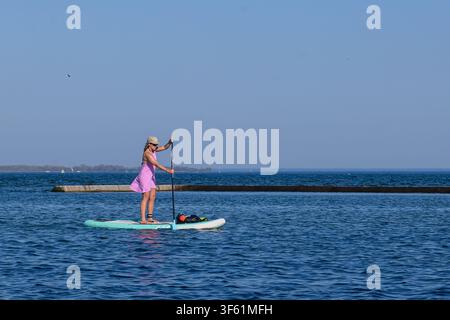 Toronto, ON, Canada - 17 mai 2026 : Une femme fait du paddle sur le lac Ontario, profitant d'une journée ensoleillée et claire dans la ville de Toronto. Banque D'Images