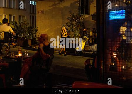 Istanbul, Turquie. 4 août 2026. Une femme fume une cigarette tandis que d’autres dînent dans un bar à Istanbul, Turquie. (Crédit image : © Moe Zoyari/ZUMA Press Wire) UTILISATION ÉDITORIALE UNIQUEMENT ! Pas pour une UTILISATION COMMERCIALE ! Banque D'Images