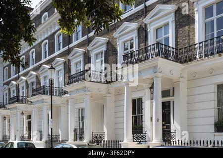 Une rangée d'élégantes maisons mitoyennes géorgiennes à Londres avec des portiques en stuc blanc classiques, des façades en brique et des balustrades en fer noir par une journée ensoleillée. Banque D'Images